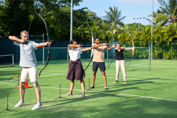 family takes aim at archery target on tennis courts of mayakoba